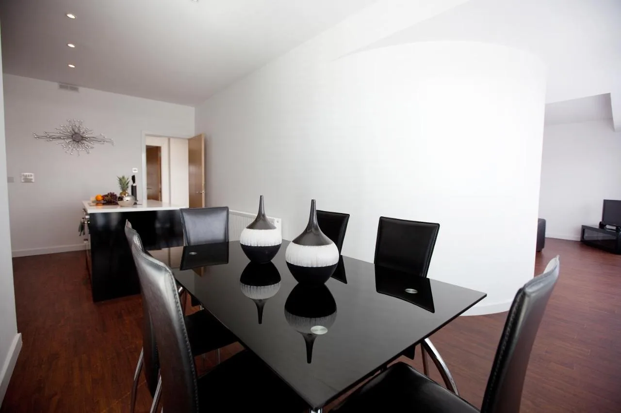 a black dining room table with chairs and vases on it at The Spires Serviced Apartments Glasgow in Glasgow